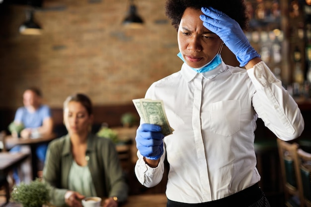 African American waitress feeling dissatisfied with a tip from a customer in a cafe