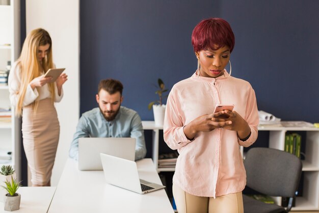 African-American woman browsing smartphone in office