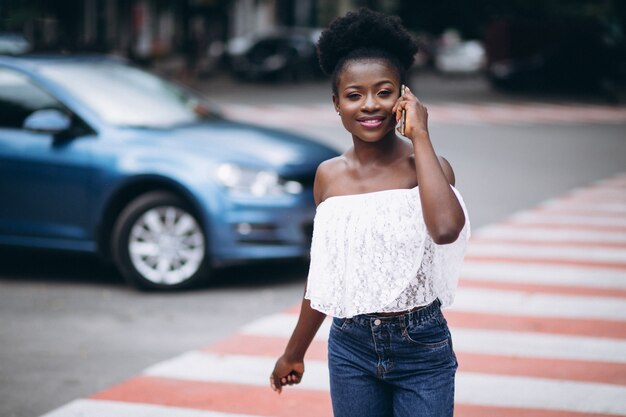 African american woman crossing road with phone