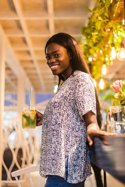 African american woman drinking cocktail lemonade in cafe at the bar.