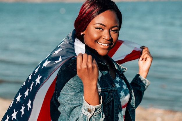 Free photo african american woman holding american flag behind back