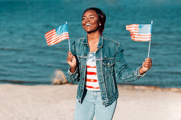 Free photo african american woman holding american flags standing on seashore