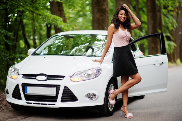 African american woman posed against white car in forest road