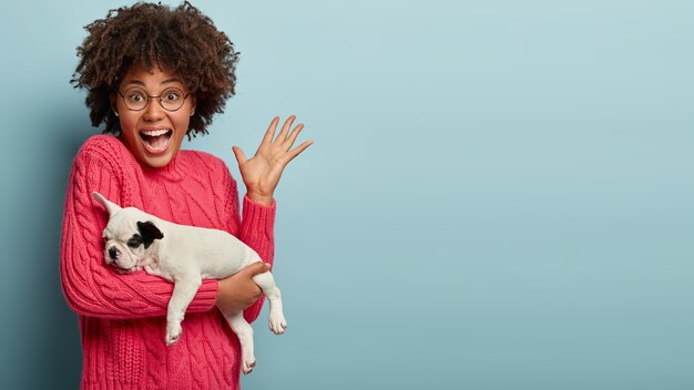 African American woman wearing pink sweater holding dog