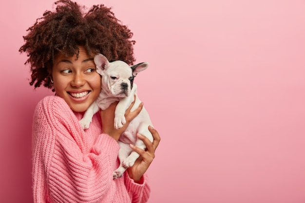 Free Photo african american woman wearing pink sweater holding puppy