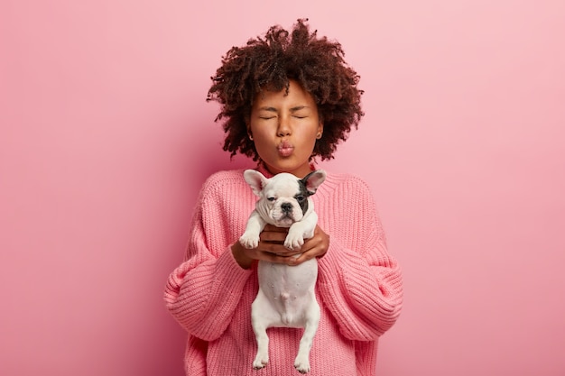 Free Photo african american woman wearing pink sweater holding puppy