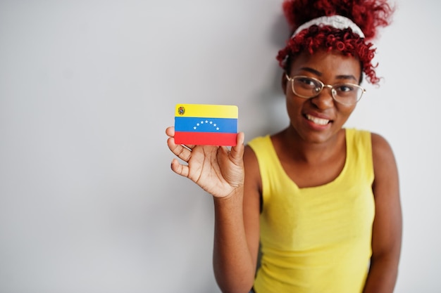 Free photo african american woman with afro hair wear yellow singlet and eyeglasses hold venezuela flag isolated on white background