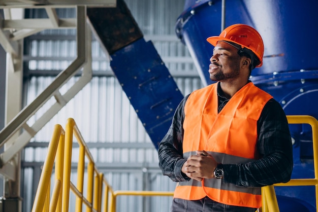 African american worker standing in uniform wearing a safety hat in a factory