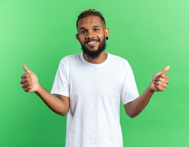 African american young man in white t-shirt looking at camera happyand cheerful smiling broadly