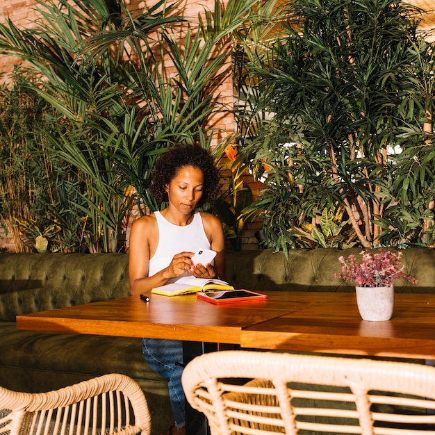 Free Photo african-american young woman using smart phone in luxury restaurant