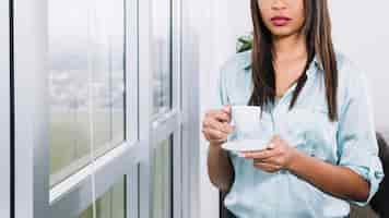 Free photo african american young woman with cup near window