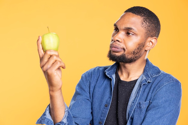 Free photo african american zero waste enthusiast looks at green apple on camera