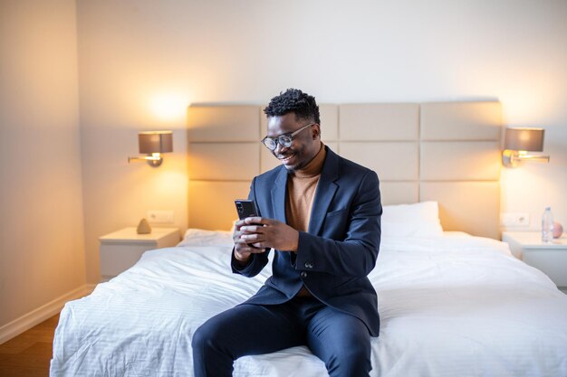 African businessman with smartphone in a hotel room Handsome man standing at the window texting Close up