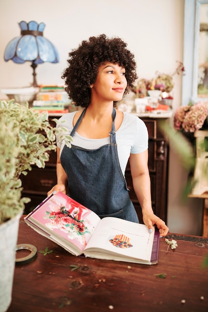 African female florist with flower photo album in shop