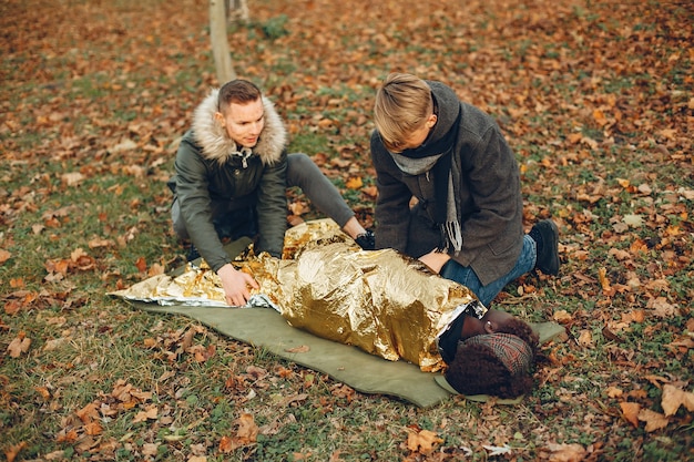 Free Photo african girl is wrapped in a warm protective film. guys help a woman. providing first aid in the park.