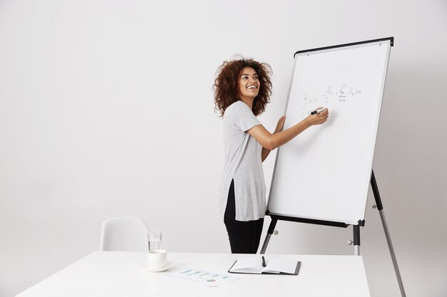 African girl smiling writing on white marker board.