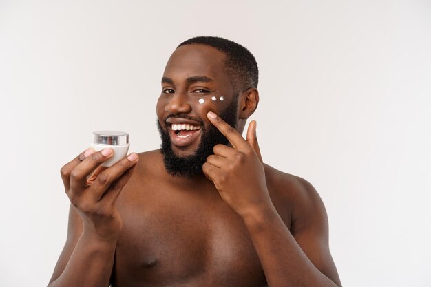 African handsome man applying cream on his face mans skin care concept