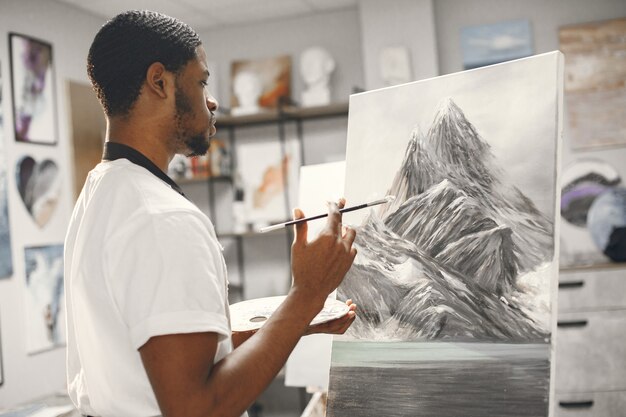 African man in painting class drawing on an easel.