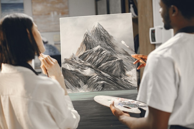 Free Photo african man and a woman in painting class drawing on an easel.