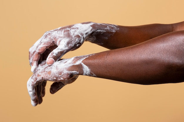 African person washing hands with soap isolated on orange