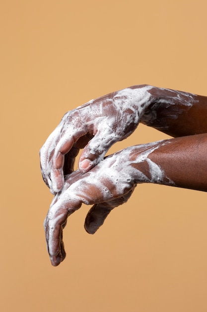 Free photo african person washing hands with soap isolated on orange