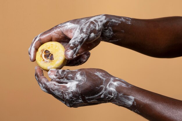 African person washing hands with soap isolated on orange