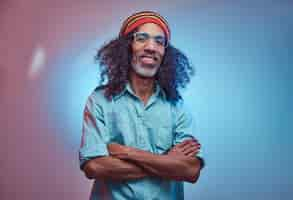 Free photo african rastafarian male smiles and looks at the camera standing with his arms crossed. studio portrait on a blue background.