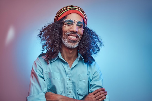 Free photo african rastafarian male smiles and looks at the camera standing with his arms crossed. studio portrait on a blue background.