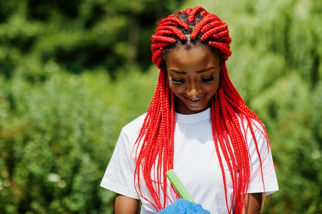 African red haired volunteer woman with clipboard in park Africa volunteering charity people and ecology concept