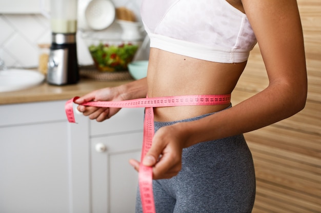 African woman is measuring her waist with a centimeter