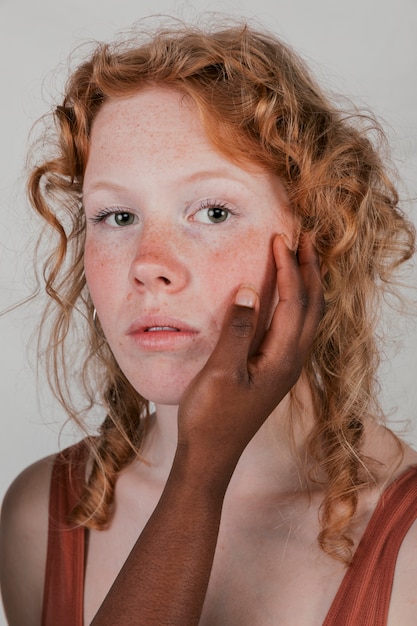 Free Photo an african woman's hand touching the cheeks of her blonde friend