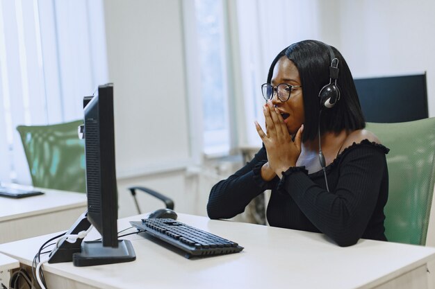 African woman sitting in computer science class. Lady with glasses. Female student sitting at the computer.