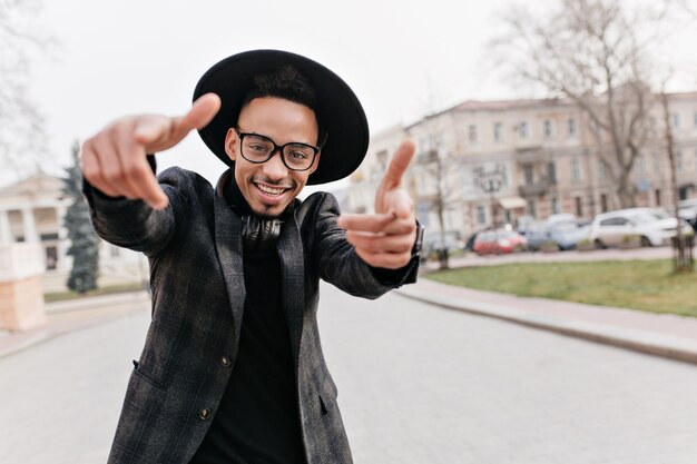 African young man in good mood dancing. Funny mulatto guy fooling around during leisure time on the street.