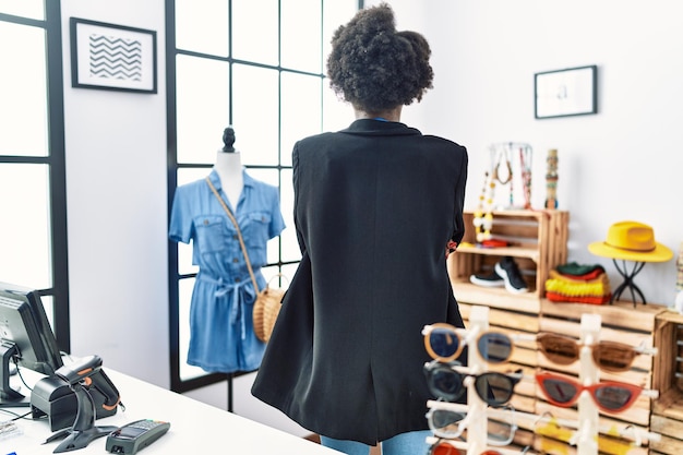 Free Photo african young woman working as manager at retail boutique standing backwards looking away with crossed arms