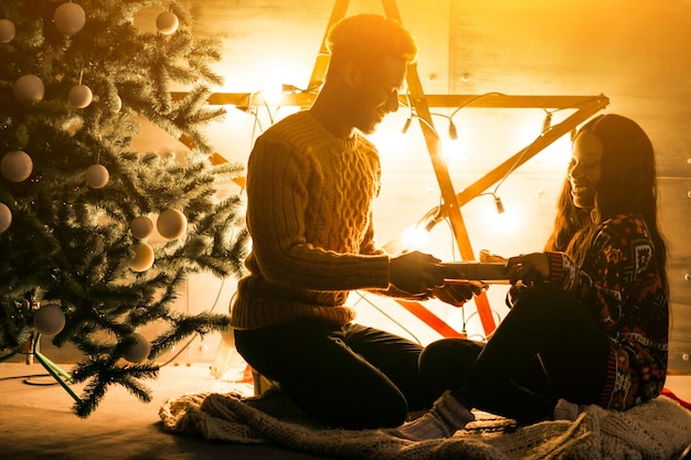 Free photo afro american couple sitting by the christmas tree