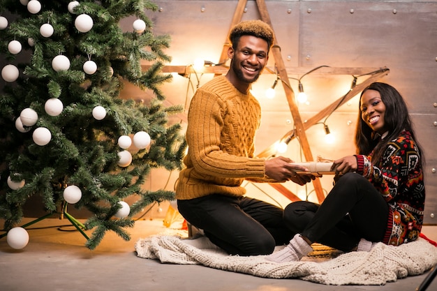 Afro american couple sitting by the Christmas tree