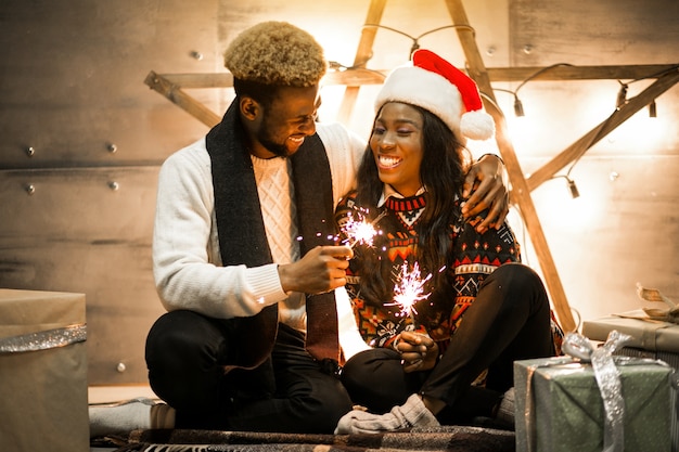 Afro american couple sitting with bengal lights