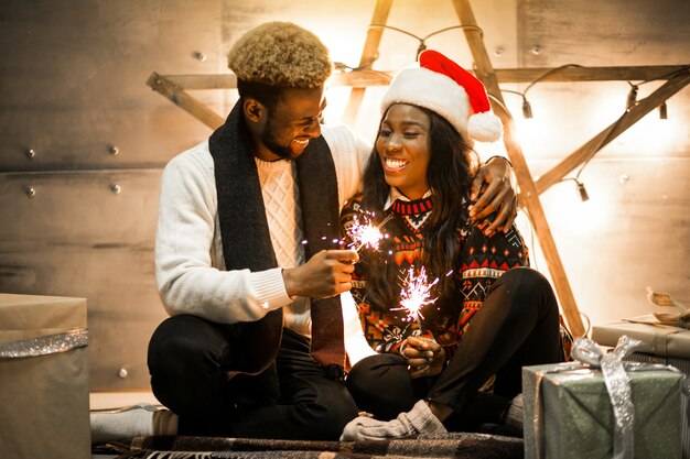 Afro american couple sitting with bengal lights