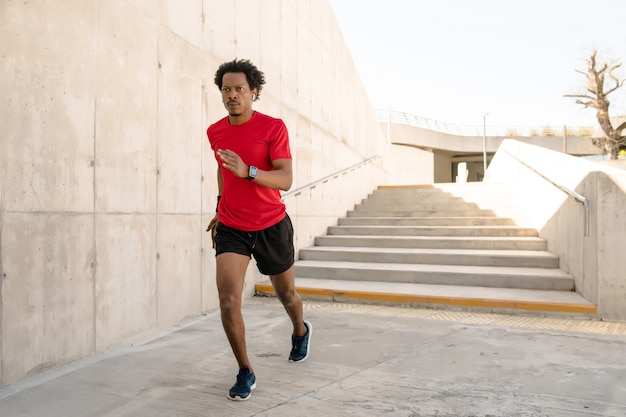 Afro athletic man running and doing exercise outdoors on the street