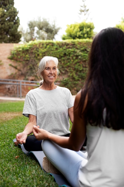 Free photo age difference female friends meeting up for yoga outdoors