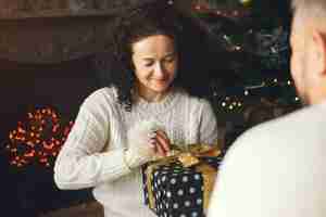 Free photo age and people concept . senior couple with gift box over lights background. woman in a white knited sweatre.