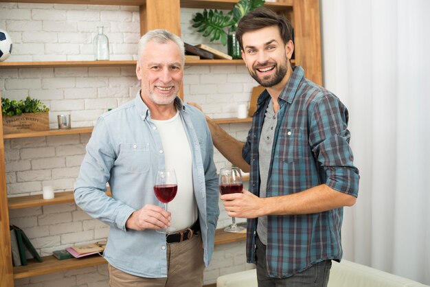 Aged man and young smiling guy with glasses of wine