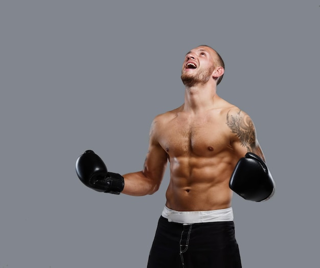 Agressive tattooed fighter isolated on a grey background.