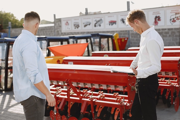 Free photo agronomist choosing a new planter. man at the outdoor ground of the shop. agricultural machinery.