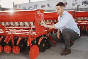 Free photo agronomist choosing a new planter. man at the outdoor ground of the shop. agricultural machinery.