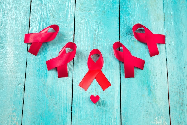 Free photo aids awareness sign red ribbons on blue wooden background . world aids day concept. the health, help, care, support, hope, illness, healthcare concept