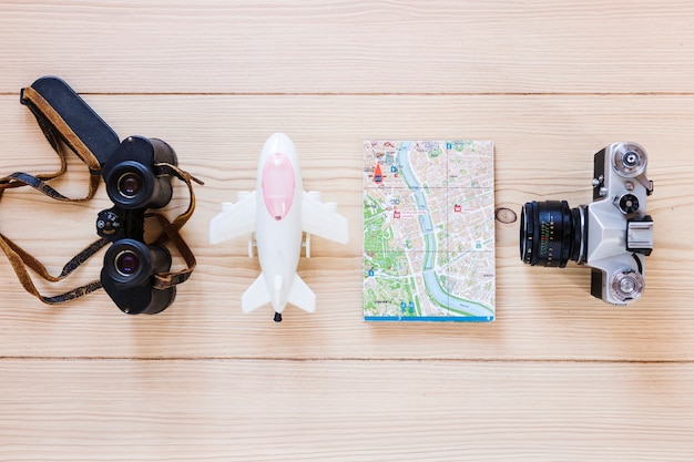 Airplane; binoculars; map and camera on wooden backdrop