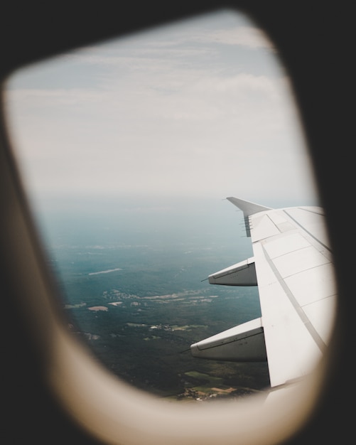 Airplane's window with the view of the green fields above and the right-wing