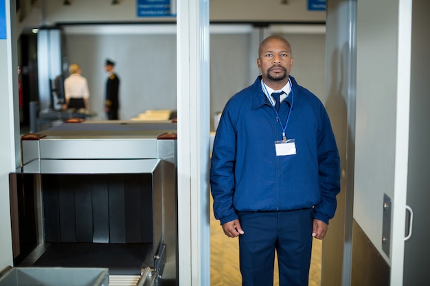 Airport security officer standing in metal detector door