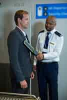 Free photo airport security officer using a hand held metal detector to check a commuter